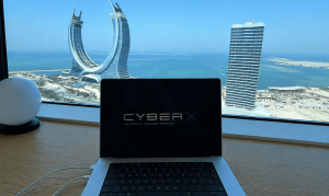CyberX laptop displaying the company logo, with the Katara Towers and Doha skyline in the background, marking the opening of CyberX's office in Qatar.