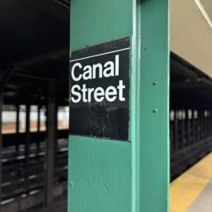 Canal Street subway station sign on a green support column on an empty platform in Lower Manhattan.