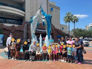 SUMMER ADVENTURE: Children and staff from Sunny Glen Children's Home pose by the marlin fountain at the Houston Aquarium during a summer trip funded by Giving Tuesday 2025.