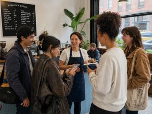 A café owner talking with a group of young customers and creators inside her shop.