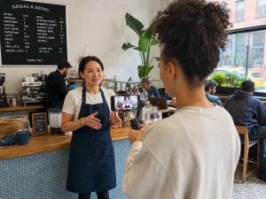 A creator filming a café owner speaking to camera inside her shop.