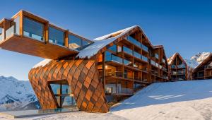 Caucasus Mandili luxury mountain resort in Gudauri, Georgia, featuring curved wooden architecture, glass balconies and snow-covered peaks.