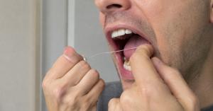 Close-up of hands attempting to floss the back molars.