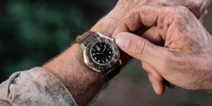 Close-up of the Luminox Adventure Watch 1300 Series on an explorer’s wrist, featuring a black dial, antique-bronze bezel and leather strap in an outdoor setting.