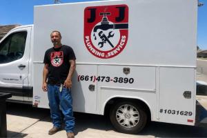 Natalio Pergis, owner of J&J Plumbing Services, standing next to a company service van in Bakersfield, California, displaying the business logo.
