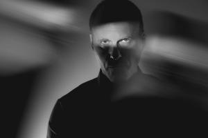 man with intense gaze through a shaft of light shared in black and white film style