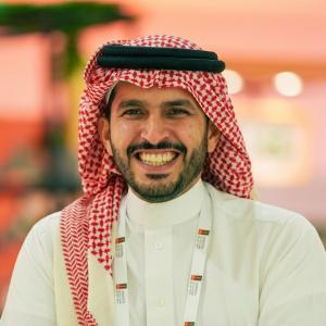 Close-up portrait of Osama Al-Awwam, Co-Founder and CEO of Roasting House, wearing traditional Saudi attire (shemagh and thobe) and smiling at the camera.