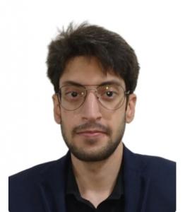 Portrait of Fasi Uddin Mir, an independent researcher in critical game design, wearing glasses and a dark jacket against a plain light background.
