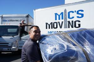 Mic’s Moving crew standing in front of company moving trucks.