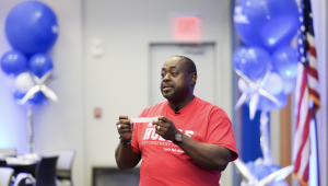 Chris Howell holding a torn paper ruler while speaking to men during In the Huddle: Stay in the Game in Dallas.