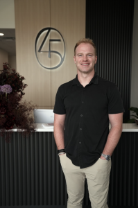 Full body shot of Dr. Kooper Ruminer founder of 405 Dental Aesthetics, at his front desk inside his office