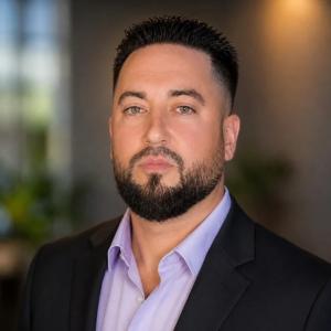 Head-and-shoulders portrait of Tampa Luxe chief executive officer Oytun Tutuncu in a dark suit and light shirt.