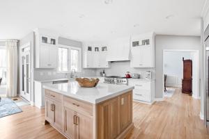 Completed kitchen remodel with custom cabinetry, a matching range hood, a large island and crown molding