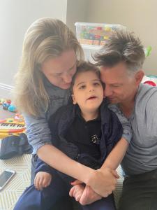 A mother and father hug their son with Rett syndrome