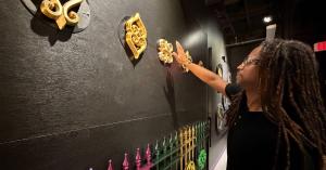 Artist Marcus Brown interacts with “Adinkra Wall: Forged Connections,” his new interactive installation at JAMNOLA inspired by West African Adinkra symbols and New Orleans ironwork.