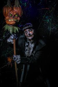 Halloween Character in make up and costume holding a pumpkin