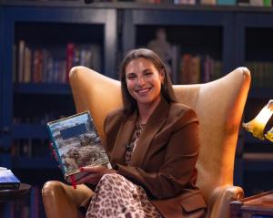 Victoria Aveyard sits in a high-backed leather library chair, posing with her copy of The Lord of the Rings.