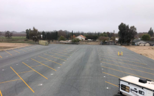 Wide aerial view of Freedom Storage Inc.'s secure, gated road-base parking lot with painted stalls for RV, boat, and vehicle storage in Visalia, California.