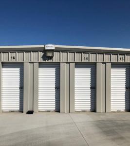 Exterior view of clean, outdoor self-storage units with white roll-up garage doors and numbered stalls at Freedom Storage Inc. in Visalia, California.