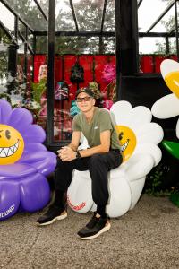 Sprayground founder David BenDavid sits on a piece of art created for the opening of Sprayground's pop-up at NYBG