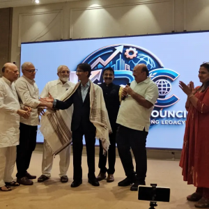 Hiten Bhuta receiving a traditional shawl on stage during the AI Agents & AI – 2055 program, with community representatives and guests applauding.