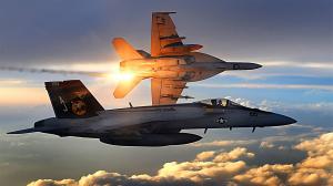 Image of two F/A-18 Super Hornets flying over clouds with sunlight