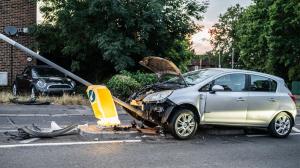 Severely damaged silver vehicle crashed into a street pole following a traffic collision.