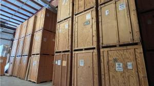 Multiple large wooden storage crates with Arnoff logos stacked high inside a modern warehouse facility.