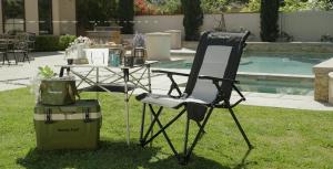 A high-back folding chair shown in an outdoor leisure setting illustrates the comfort-focused segment of SUNSHINE Outdoor’s portable seating portfolio.