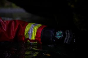 Luminox watch glowing on a gloved wrist in near-dark conditions, with illuminated hour markers and hands clearly visible.