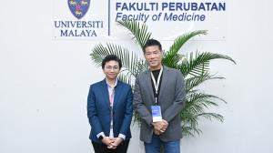Zen Koh and Associate Professor Dr Norhamizan Hamzah standing in front of the Universiti Malaya Faculty of Medicine signage.