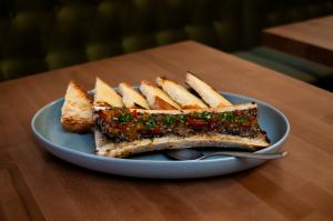 Roasted bone marrow topped with mushroom XO, onion honey jam and herbs, served with toasted sourdough on a blue plate at Gunny’s Pub.