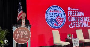 Sabin Howard, sculptor of the National World War I Memorial’s A Soldier’s Journey and creator of the Grand Liberty Arch, speaks at the Steamboat Institute’s 18th Annual Freedom Conference in Beaver Creek, Colorado, with the America 250 emblem behind him,
