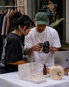 Photographer and independent jewelry seller reviewing product photos at an outdoor Pop-Up table.