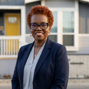Yvette Hitchens, founder of The MH Trainer, wearing a navy blazer and standing outside a manufactured home.