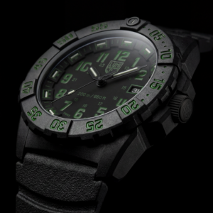Close-up of a black Luminox Navy SEAL watch with green accents, rugged CARBONOX case, dive bezel and black rubber strap against a dark background.