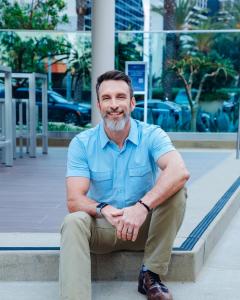 Mike Michalowicz seated outdoors, smiling, in a light-blue short-sleeved shirt.