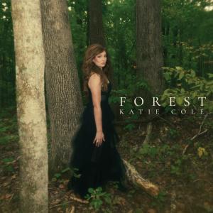 Katie Cole 'Forest' album cover. Katie is standing in a wooded area wearing a black dress