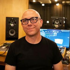 caucasian man with short hair and black eyeglasses in a recording studio