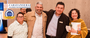 Four diverse adults smiling at a networking event hosted by Caravanserai Alliance for Entrepreneurs.
