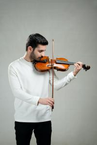 GRAMMY-nominated composer Mehran Matin performing violin in a studio portrait.