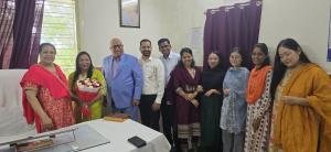 Group photo featuring Dr. Matthew K. Thomas and Mrs. A.M. Thomas, parents of Dr. Michael Thomas and Dr. Praisey Thomas (née Yesudas), with Dr. Kumre holding the bouquet of flowers, alongside Pastor Nikhil Raj Gupta, Dr. Jayanta Chhinchani and team members.