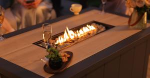 Built-in fire pit table from the Mirador Siena 4-Piece Seating Set with a linear flame feature, creating a warm setting for evening outdoor gatherings.