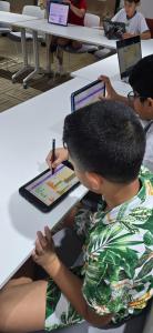 Students using tablets and laptops for coding activities during the Mind Base Education STEM Summer Program in Abu Dhabi.