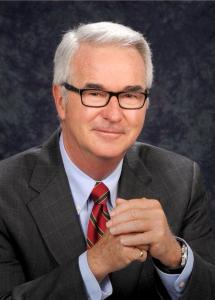 Formal portrait of Judge Frederick Rick De Furia wearing a dark suit, striped red tie and glasses.