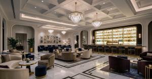 Elegant hotel lounge and bar with crystal chandeliers, upholstered seating, marble floors and an illuminated bottle display.