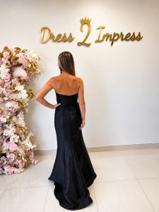 Back view of a black strapless evening gown featuring covered buttons and a fitted silhouette at Dress 2 Impress boutique.