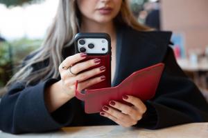 Woman holding an iPhone with a red O2 Leather leather wallet case open to show the card holder.