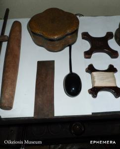 A workbench at the OIKEIOSIS MUSEUM studio in Seoul, laid with a wooden mallet, a leather strop, a speckled lacquer box, spools of silk thread, and a black glazed ceramic piece on a cord.
