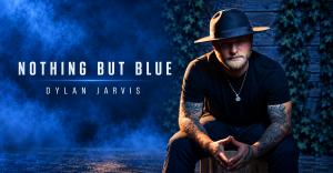 Country artist Dylan Jarvis seated in a dark hat and black shirt against a blue smoky backdrop, with “Nothing But Blue” displayed beside him.